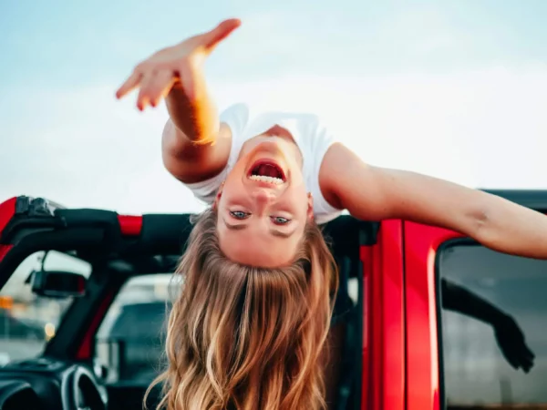 smiling girl reaching out over top of car
